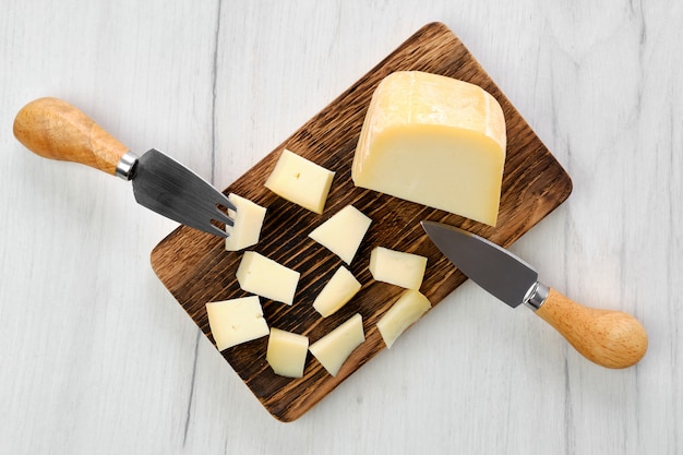 La vista superiore del formaggio di capra ha tagliato sui pezzi sul tagliere di legno