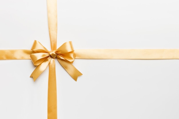 Top view of gold ribbon rolled and yellowbow isolated on colored background Flat lay with copy space