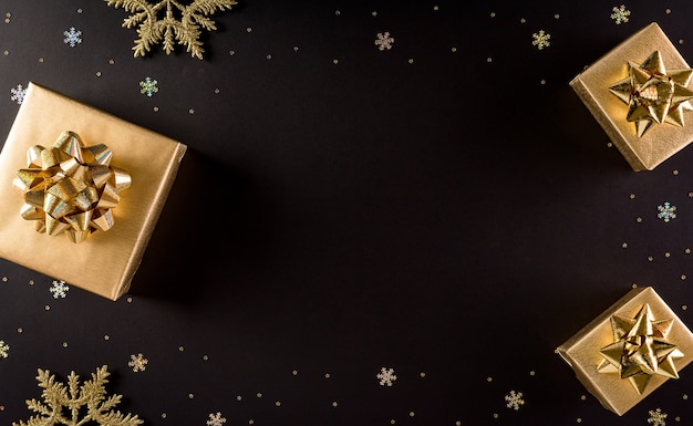 Top view of golden christmas boxes on black background with copy space for text