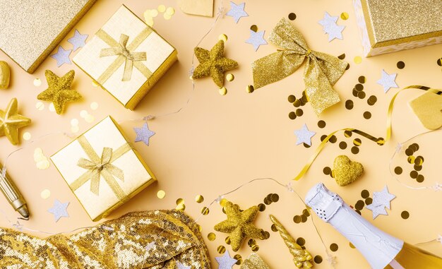 Top view of golden party decorations with confetti and gift boxes flat lay