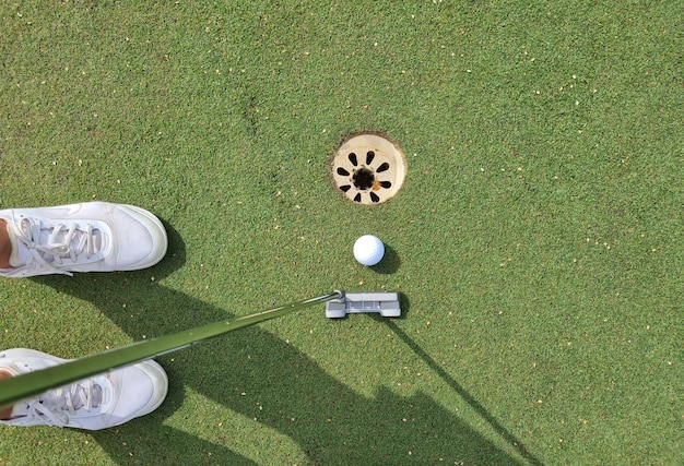 Top view of golf ball with club on a green field in hall