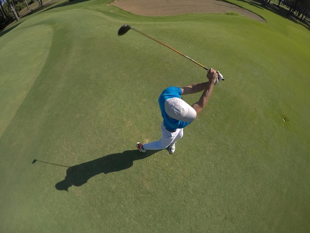 Top view of golf player hitting shot with club on course at\
beautiful morning