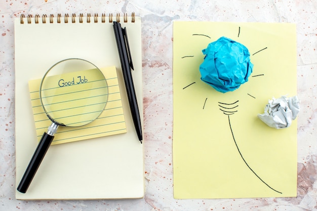 top view good job written on sticky note notebook pen lupa idea light bulb concept with crumpled paper on table