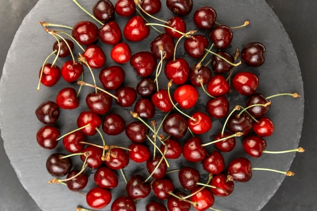 Top view gray plate with ripe sweet red cherry. Seasonal berries. Homemade organic cherries.