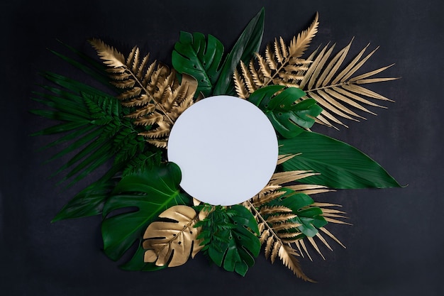 Top view of green and gold tropical leaves on old  black wood floor