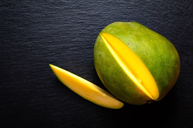 Top view green mango on black slate stone board