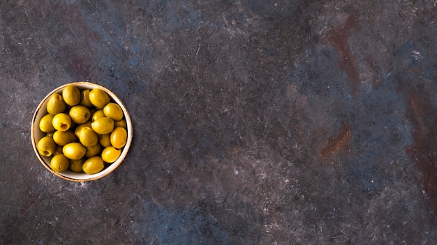 Photo top view of green olives in a bowl.