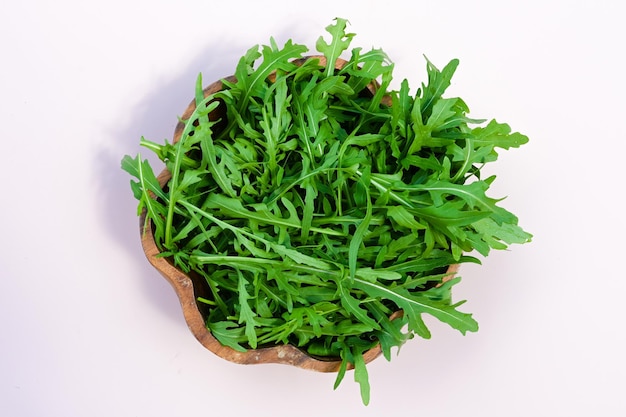 Top view of green ripe arugula leaves on wooden bowl
