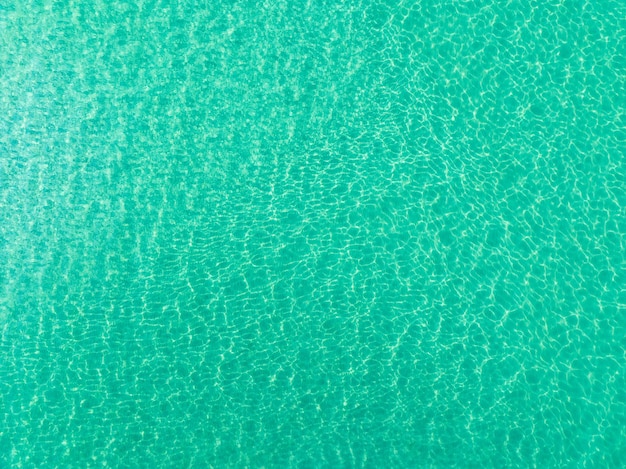 Top view of green sea surface shot in the open sea from\
aboveamazing nature background of turquoise water surface waves\
reflecting the sunlight