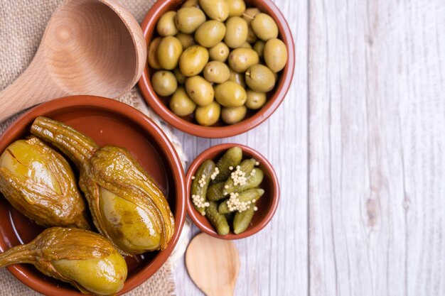 Photo top view of green seasoned olives almagro aubergine and pickles in vinegar in red bowls