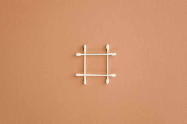 Top view of grid made of cotton swabs on beige background