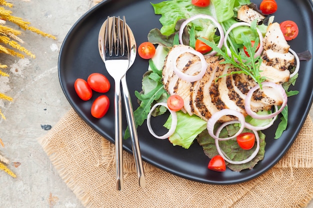 Vista dall'alto. insalata di pollo alla griglia con pomodori e cipolle sulla piastra nera