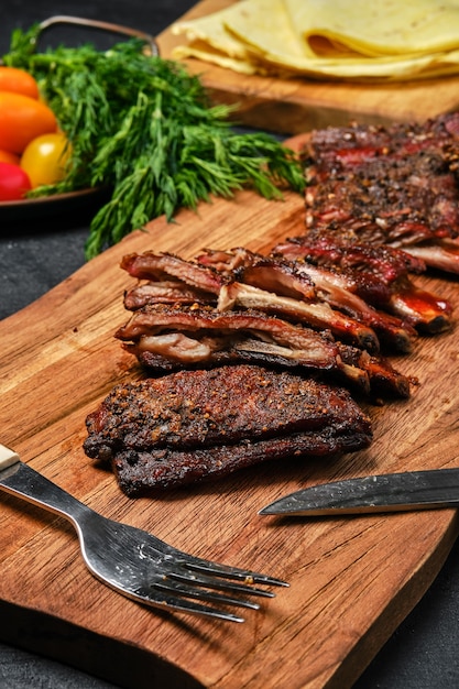 Top view of grilled lamb breast ribs on wooden cutting board