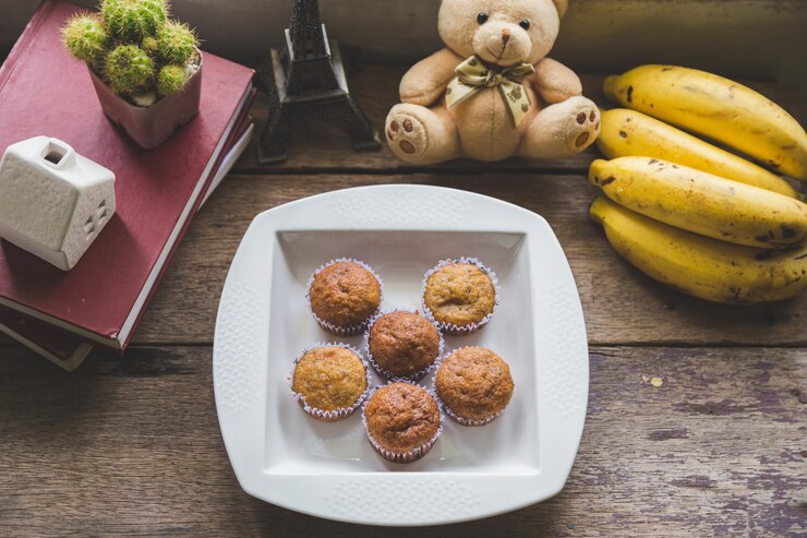 Photo top view group of banana cup cake in a white plate with a cup of milk and banana fruit