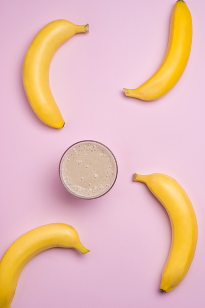 Vista dall'alto. gruppo di banane e frullato di banana su sfondo rosa.