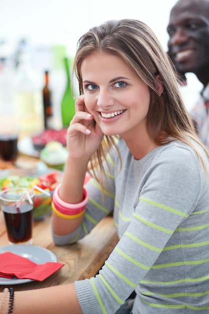 Top view of group of people having dinner together while\
sitting at wooden table food on the table people eat fast food the\
girl is talking on the phone