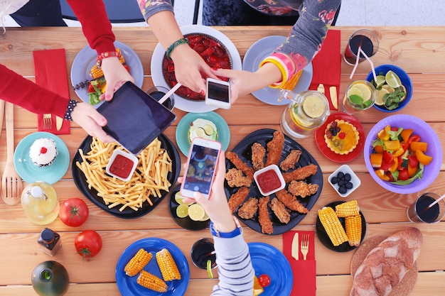 Foto vista dall'alto di un gruppo di persone che cenano insieme seduti a un tavolo di legno cibo sul tavolo le persone mangiano fast food fotografare il cibo