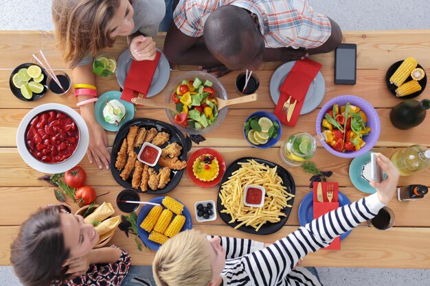 木製のテーブルに座って一緒に夕食を食べている人々のグループの上面図テーブルの上の食べ物人々はファーストフードを食べる