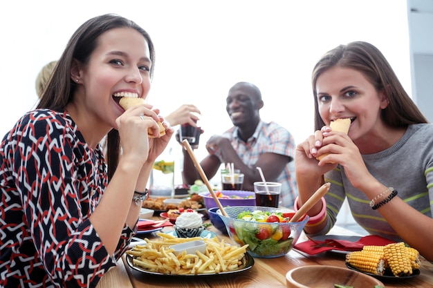 Top view of group of people having dinner together while\
sitting at wooden table food on the table people eat fast food