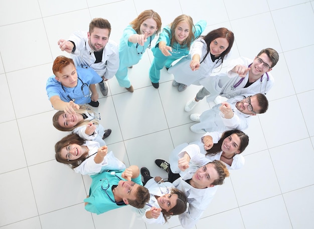 Top view a group of smiling doctors pointing at you