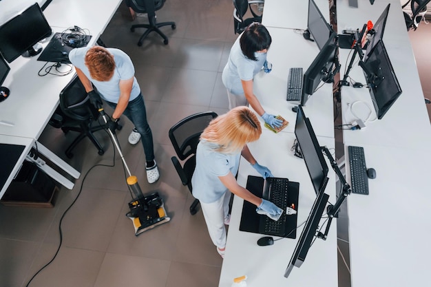 Foto vista dall'alto un gruppo di lavoratori pulisce insieme l'ufficio moderno durante il giorno