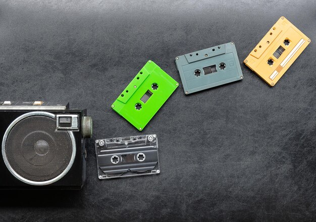 Photo top view half retro radio and colorful cassette tape on black floor