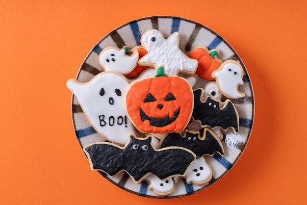 Photo top view of halloween festive decorated icing gingerbread sugar cookies on orange background with copy space and flat lay layout