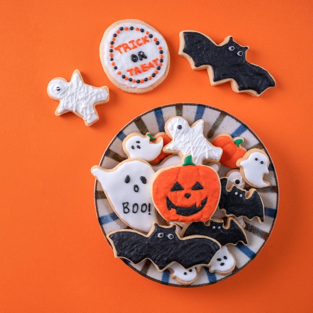 Top view of halloween festive decorated icing sugar cookies on\
orange background