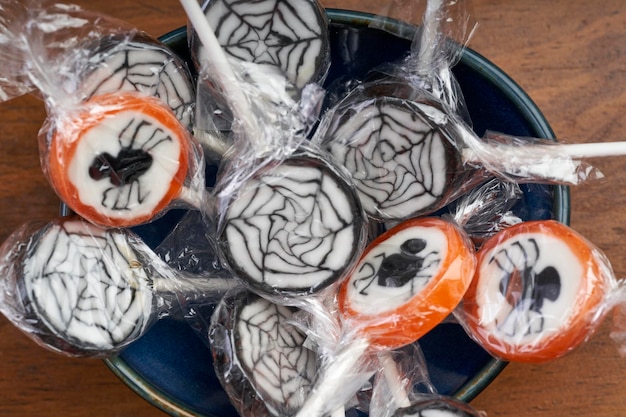 Top view of halloween lollipops with spiders and webs in bowl