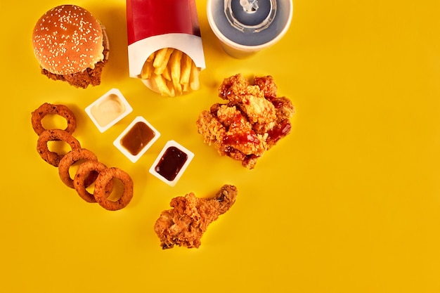 Вид сверху гамбургер, картофель фри и жареная курица на желтом фоне Скопируйте место для текста