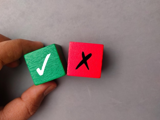 Top view hand holding colored block with symbol right and wrong on a gray background