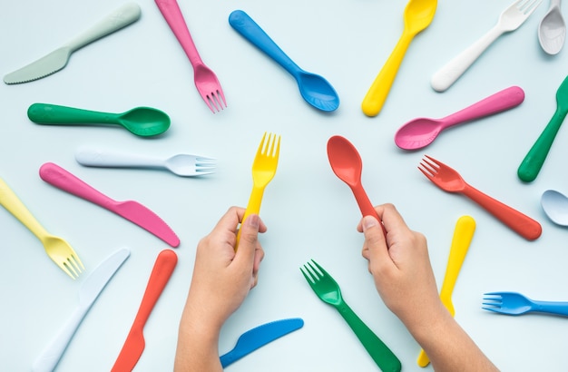 Top view of hand holding colorful spoon and fork