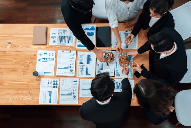 Photo top view hand holding gear by group of businesspeople on table in harmony office