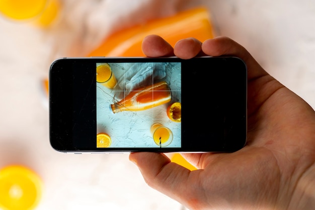 携帯電話を持って携帯電話の食べ物の写真を撮っている手の上面図