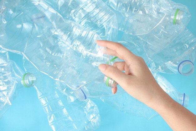 Top view of hand holding plastic bottles on blue background recycle and world environment day concept