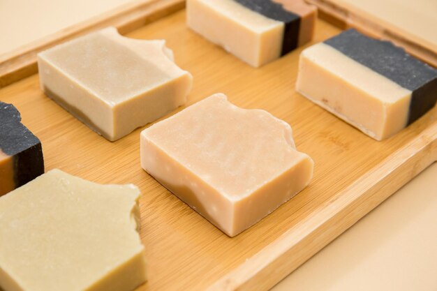 Top view of hand made soap bar on wooden tray with beige background