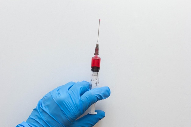 Top view of hand in medical glove holding syringe barrel with vitamin group B for injection on the white background