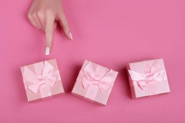 Top view hand woman chooses pink gift box for valentines day