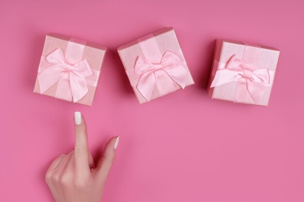 Top view hand woman chooses pink gift box for valentines day