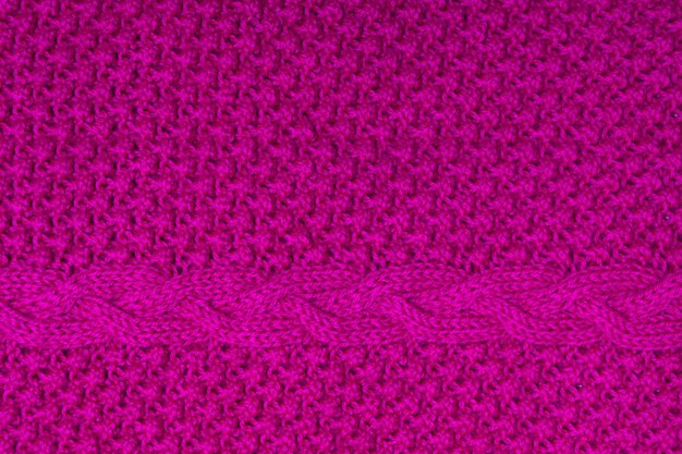 Top view of handmade bright fuchsia pink knitted texture with plait