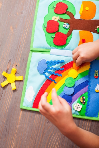 Top view of the hands of a child exploring rainbow colors with help of developing book