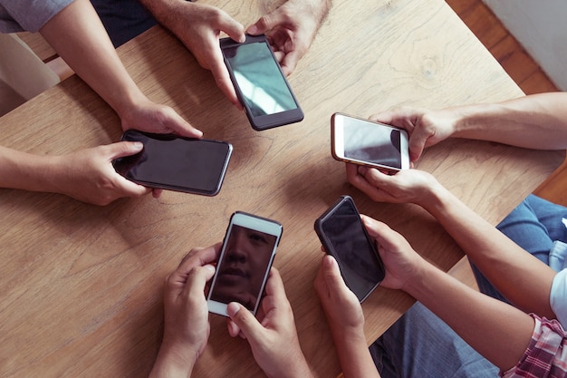 Foto le mani di vista superiore circondano facendo uso del telefono in caffè