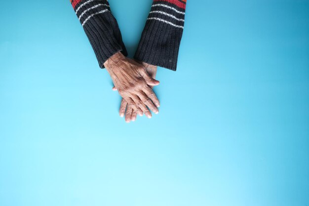 Photo top view of hands of a elderly person on blue background