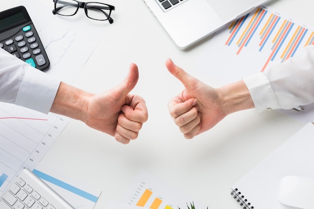 Photo top view of hands giving thumbs up over desk