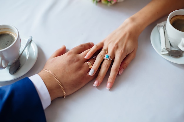 Top view hands of newlyweds on table in cafe. newlyweds