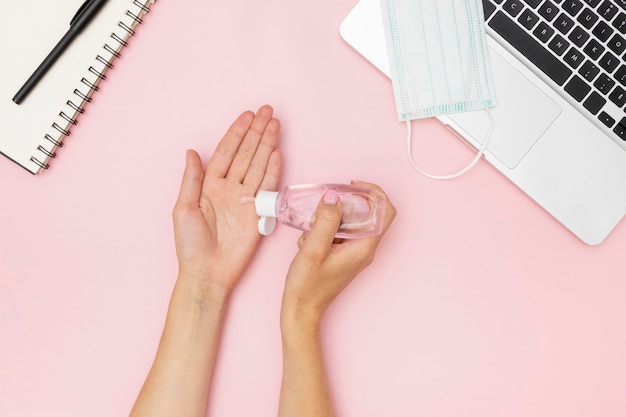 Photo top view of hands using hand sanitizer on desk