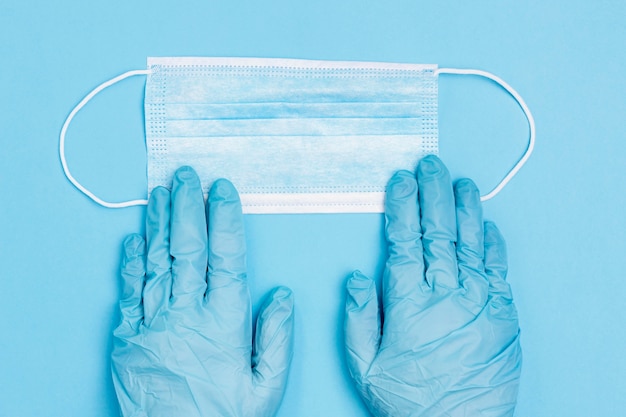 Top view of hands wearing surgical gloves with medical mask