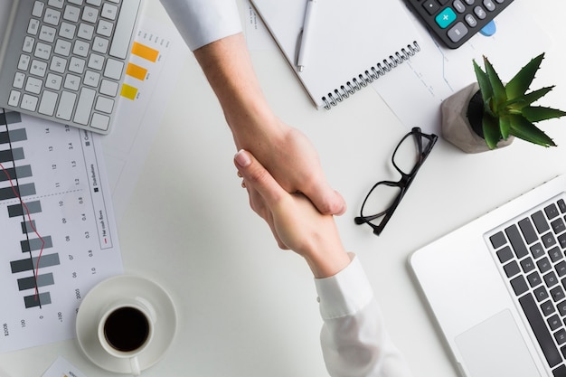 Photo top view of handshake over work desk