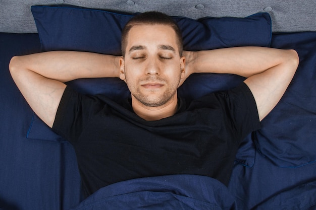 Foto vista dall'alto di un bel giovane che dorme comodamente sul letto nella sua camera da letto di notte camera da letto bachelor sonno profondo