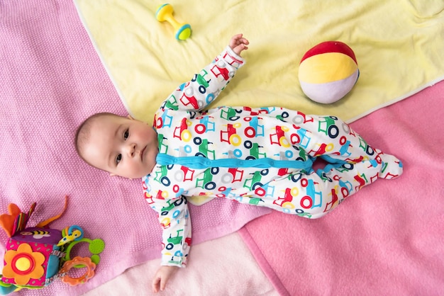 top view of happy beautiful newborn baby boy lying on colorful blankets while playing first games at home